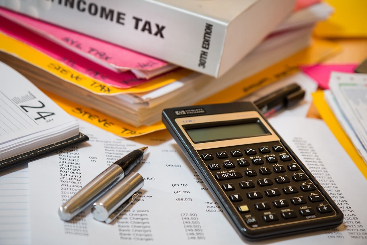 Foto de una calculadora, unos bolis y una carpeta donde guardar todo lo relacionado con el IS