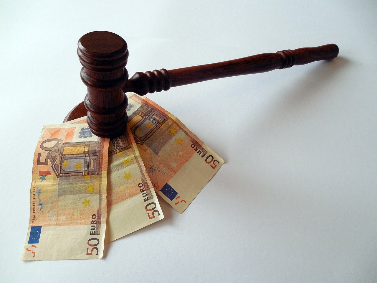 Foto de un mazo de juez con tres billetes de 50 euros debajo, imagen que ilustra el artículo de Ponter Abogados y Asesores sobre "Proporcionalidad en la sanción por no consignar cuotas en la autoliquidación del IVA"